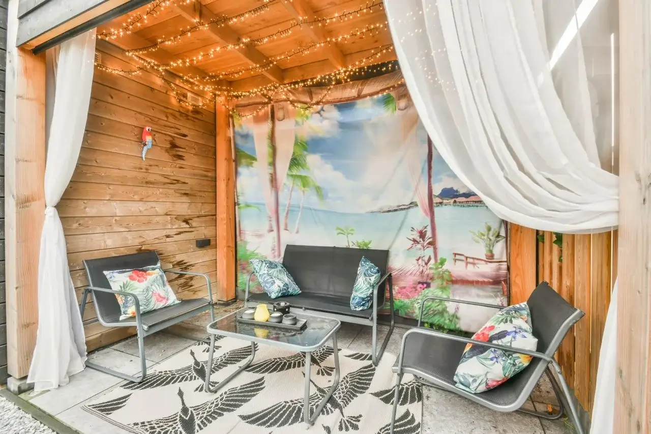 Cozy outdoor seating area with tropical decor and string lights.